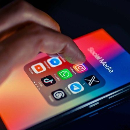 Symbolfoto: Ein Mensch bedient ein Smartphone auf dem die Symbole diverser Social Media Apps zu sehen sind.