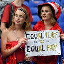 US-Fans halten ein Schild mit "Gleichem Spiel = Gleicher Bezahlung" hoch