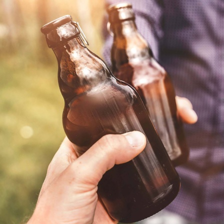Zwei Menschen stoßen mit Bierflaschen an