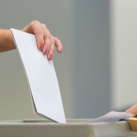 Eine Wählerin wirft bei der Stimmabgabe zur Landtagswahl in Sachsen den Wahlzettel in einem Wahllokal in eine Wahlurne.