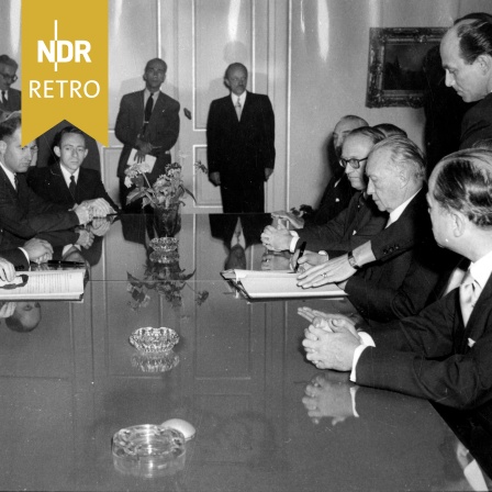 Der israelische Außenminister Moshe Sharett (links) und der deutsche Bundeskanzler Konrad Adenauer (rechts) unterzeichnen einen Wiedergutmachungsvertrag am 12. September 1952
