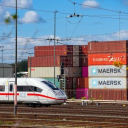 Ein ICE-Zug fährt an gestapelten Containern am Berliner Westhafen vorbei.