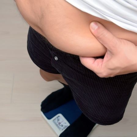 Ein Mann umfasst seinen Bauch mit den Händen. 