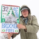 Wanderer Benno Schmidt, besser bekannt als Brocken Benno, steht mit einem Schild zur Erinnerung an die Brockenöffnung am 3.12.1989 auf dem Brocken. 