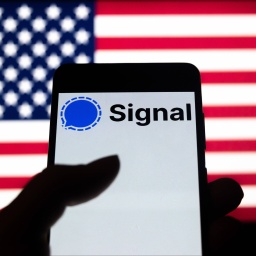 Foto-Illustration zeigt ein Logo der Signal-App auf einem Smartphone-Bildschirm mit einer US-Flagge im Hintergrund 