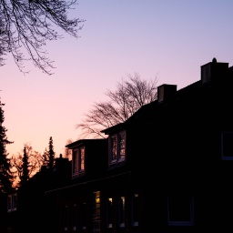 Die Sonne geht am Morgen hinter einem Wohnhaus auf.