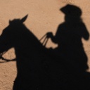 Ein Cowboy reitet auf seinem Pferd, zu sehen ist nur sein Schatten.