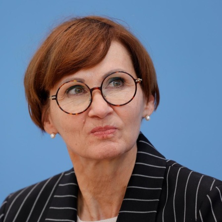 Die Bundesministerin für Bildung und Forschung, Bettina Stark-Watzinger, schaut nachdenklich nach oben. Hinter ihr die blaue Wand der Bundespressekonferenz.