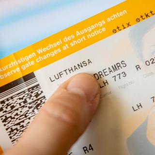 Ein Mann hält ein Flugticket der Lufthansa in der Hand