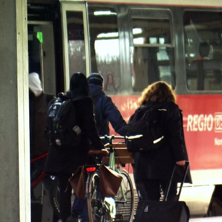 Fahrgäste mit Fahrrädern sowie eine Zugbegleiterin steigen in eine Regionalbahn.