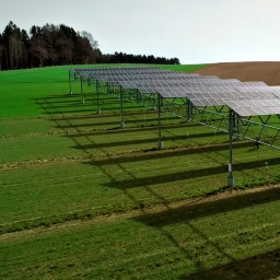 Ein Feld auf einem Hügel, auf dem Photovoltaik-Anlagen stehen. 