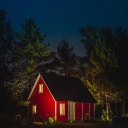 Ein kleines rotes Haus bei Nacht in einem Wald.