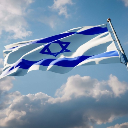 Flagge Israels vor blauem Himmel mit Wolken.