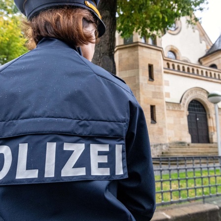 Eine Polizistin steht vor der Synagoge. Nach dem Anschlag auf eine Synagoge in Halle/Saale hat die Polizei ihre Präsenz vor jüdischen Einrichtungen im Freistaat erhöht.