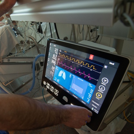 Ein Arzt bedient eine Beatmungsmaschine auf einer Intensivstation.