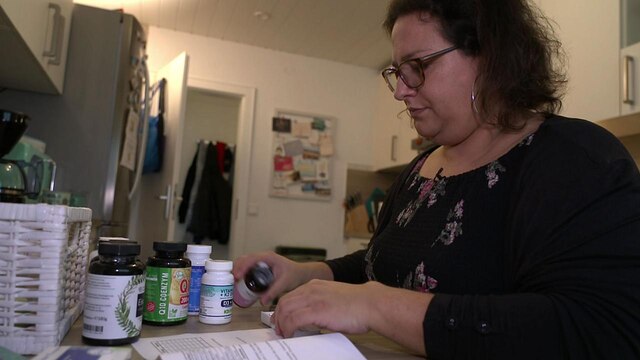 Eine ungeimpfte Frau richtet ihre Medikamente nach einer Corona-Erkrankung.