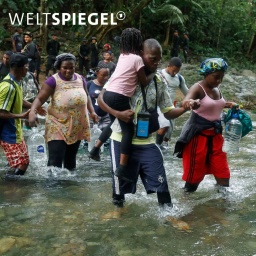 Migrantinnen und Migranten überqueren einen Fluss im Darién-Dschungel