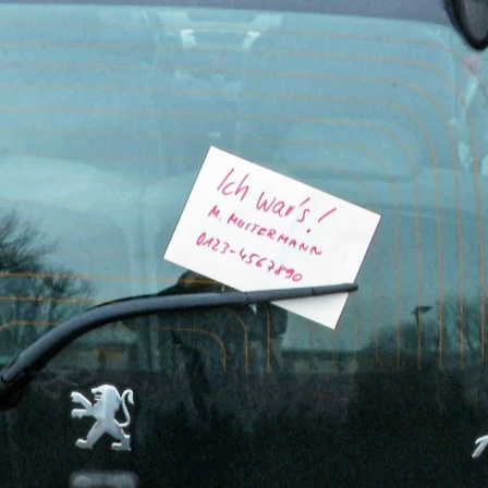 Ein Zettel mit dem Text "Ich Wars" und einer Telefonnummer am Schiebenwischer eines Autos angebracht