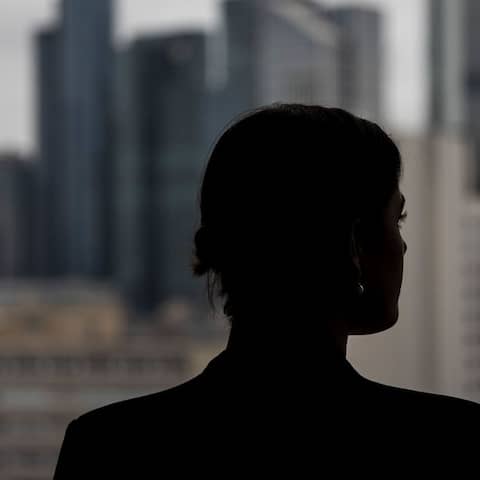 Eine Frau schaut aus einem Bürofenster auf weitere Hochhäuser (Bild: picture alliance/dpa/Hannes P. Albert)