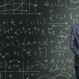 Ein Mann steht vor einer Tafel mit Formeln