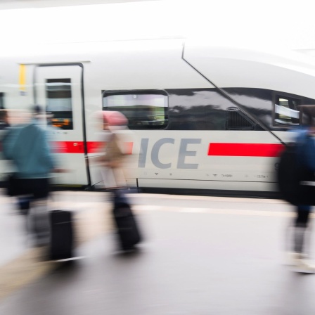 Reisende stehen auf dem Bahnsteig im Hauptbahnhof Hannover, während ein ICE einfährt (Bild: Julian Stratenschulte/dpa)