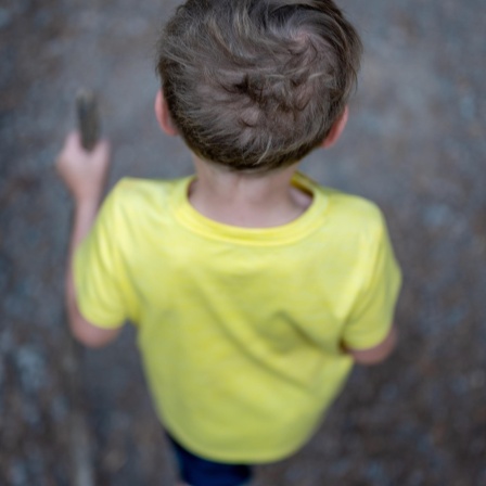 Man sieht einen Jungen von hinten und oben einen Weg entlang laufen.