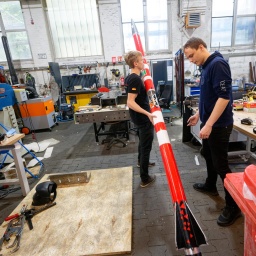 Die Studenten Florian Schuler (l) und Johann Schepke vom Space Team Aachen stehen mit ihrer Rakete in der Werkstatt. Der Flugkörper soll mit zweifacher Schallgeschwindigkeit von einem Schiff von der Nordsee aus starten.