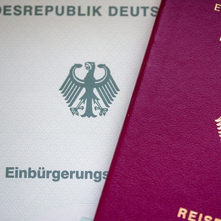 Eine Einbürgerungsurkunde der Bundesrepublik Deutschland (l) und ein deutscher Reisepass liegen auf einem Tisch.