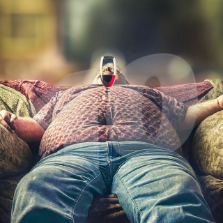 Korpulenter Mann liegt auf einem Sofa und schläft, auf dem Bauch ein Weinglas balancierend.