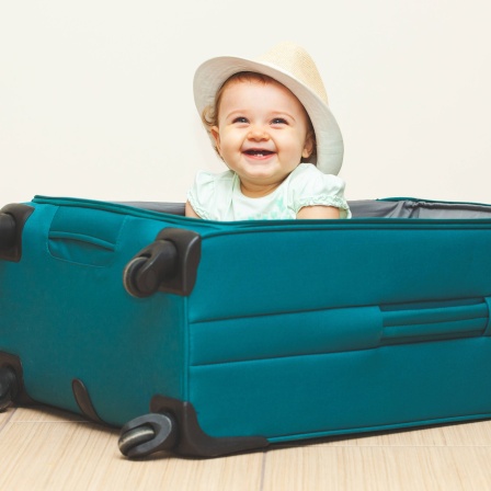 Ein Baby sitzt in einem Reisekoffer.