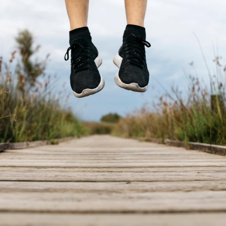 Der Freudensprung eines Joggers auf einem Steg