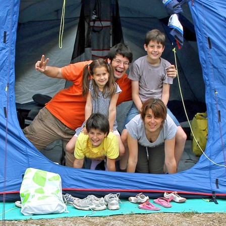 Eine junge Familie sitzt am Eingang in einem Zelt.