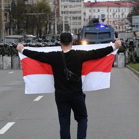 25.10.2020, Belarus, Minsk: A man holds a white-red-white Belarus flags as he attends an opposition rally to reject the presidential election results in Minsk, Belarus.