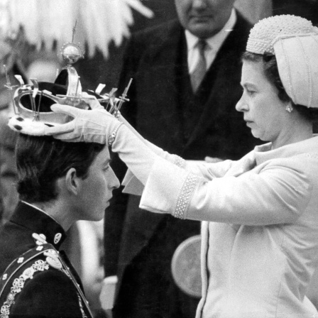 Charles kniet bei seiner Invesitur zum Prince of Wales am 1. Juli 1969 vor seiner Mutter, Elizabeth II, als die Queen im die juwelenbesetzte Goldkrone in Caernarfon Castle auf den Kopf setzt