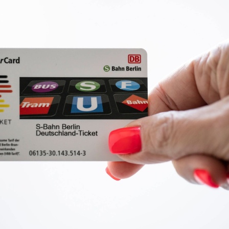 Eine Frau hält ein Deutschlandticket in der Hand