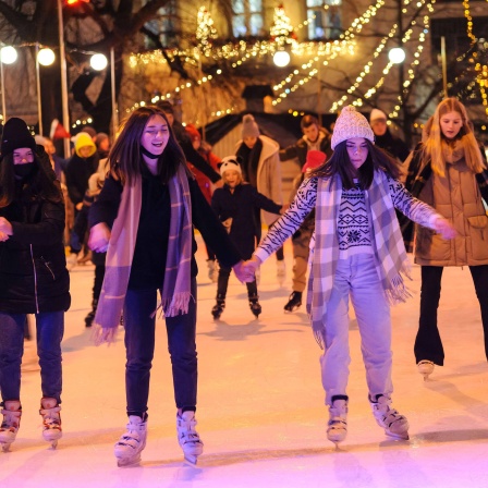 Mädchen laufen Schlittschuh auf weihnachtlich dekorierter Eisfläche