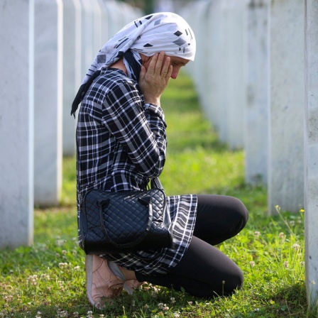 Eine bosnisch-muslimische Frau trauert neben dem Grab eines Verwandten, der dem Völkermord von Srebrenica zum Opfer gefallen war, im Gedenkzentrum in Potocari, Bosnien. 
