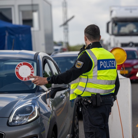 Ein Bundespolizist zieht auf der A64 ein Fahrzeug zur Kontrolle der Insassen raus.