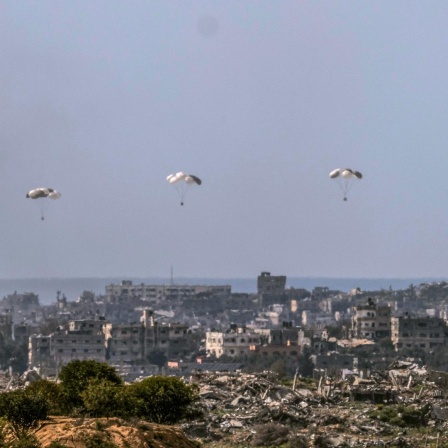 An Fallschirmen befestigte Hilfslieferungen sind in der Luft über zerstörten Häusern im Gazastreifen.