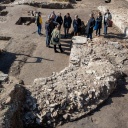 Eine kleine Gruppe Menschen steht auf den ausgegrabenen Mauerresten einer großen Kirche in der Sonne.