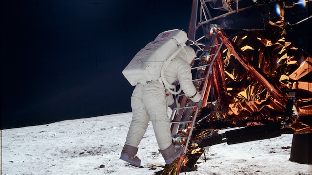 Ein Astronaut im Anzug klettert auf einer Leiter von seiner Raumkaspel auf die Mondoberfläche.