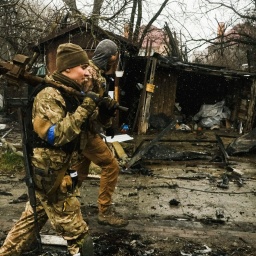 Ukrainische Soldaten inspizieren die Trümmer einer zerstörten russischen Panzerkolonne auf einer Straße in Butscha, einem Vorort nördlich der Hauptstadt.