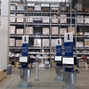 Auf dem Foto vom Ikea Einrichtungshaus in Kaarst sind im Vordergrund Infoterminals zu sehen, im Hintergrund ein Hochlager voller Kartons und Verpackungen.