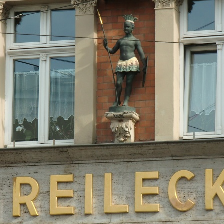 Eine männliche Skulptur an einer Hauswand der Mohrenapotheke in Halle