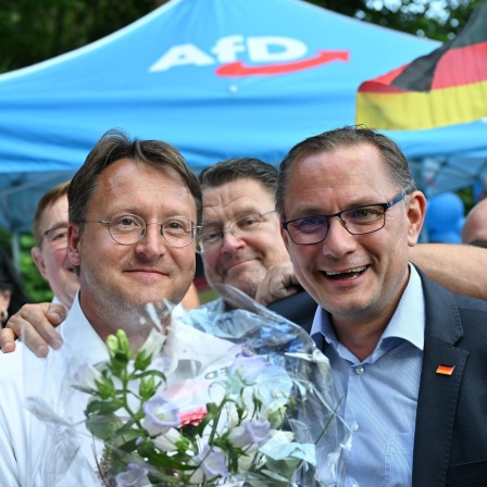 Björn Höcke und Tino Chrupalla stehen rechts und links neben Robert Sesselmann bei einem Gartenfest der AfD.