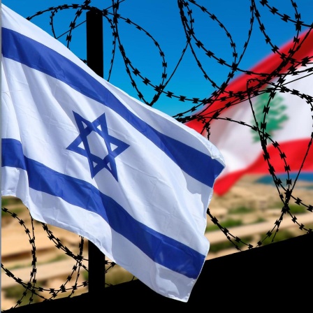 Die israelische und die libanesische Flagge wehen an einer Grenzanlage mit Stacheldraht.