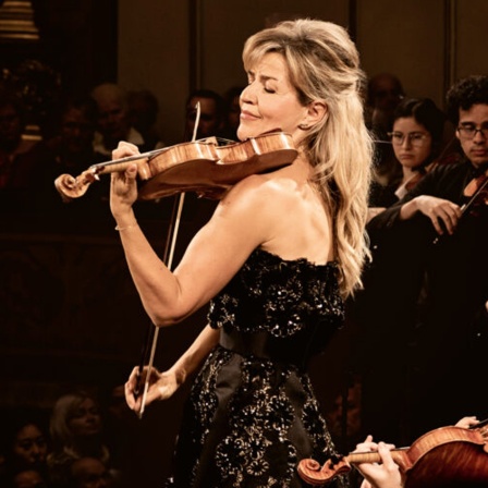 Anne-Sophie Mutter, Stargeigerin, steht zwischen anderen Streichern und spielt Geige.