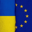 [M] Die Nationalflagge der Ukraine und die Flagge der Europäischen Union auf einer Wand mit einem vertikalen Absatz bzw. Riss in der Mitte und zwei unterschiedlichen Putzarten. Foto mit Composing als Symbolbild für das Verhältnis zwischen der Ukraine und der EU.