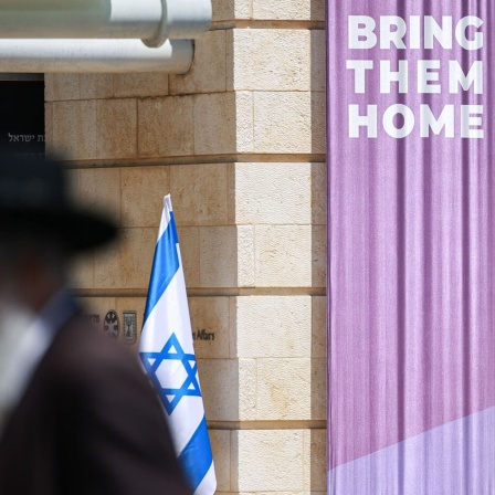 Mit Blick auf die von der Hamas verschleppten israelischen Geiseln steht "Bring them home" (Bringt sie heim) auf einem Transparent in Jerusalem, im Vordergrund geht ein orthodoxer Jude vorbei. (Bild: picture alliance/dpa/Hannes P. Albert)