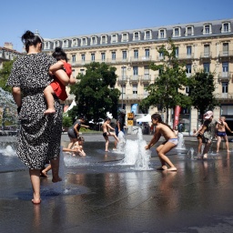 Kinder kühlen sich an einem Stadtbrunnen während der Hitzewelle 2022 in Toulouse.